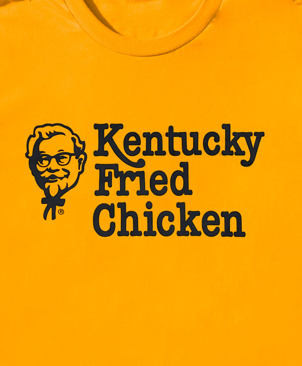 close up of gold KFC t shirt with black KFC logo