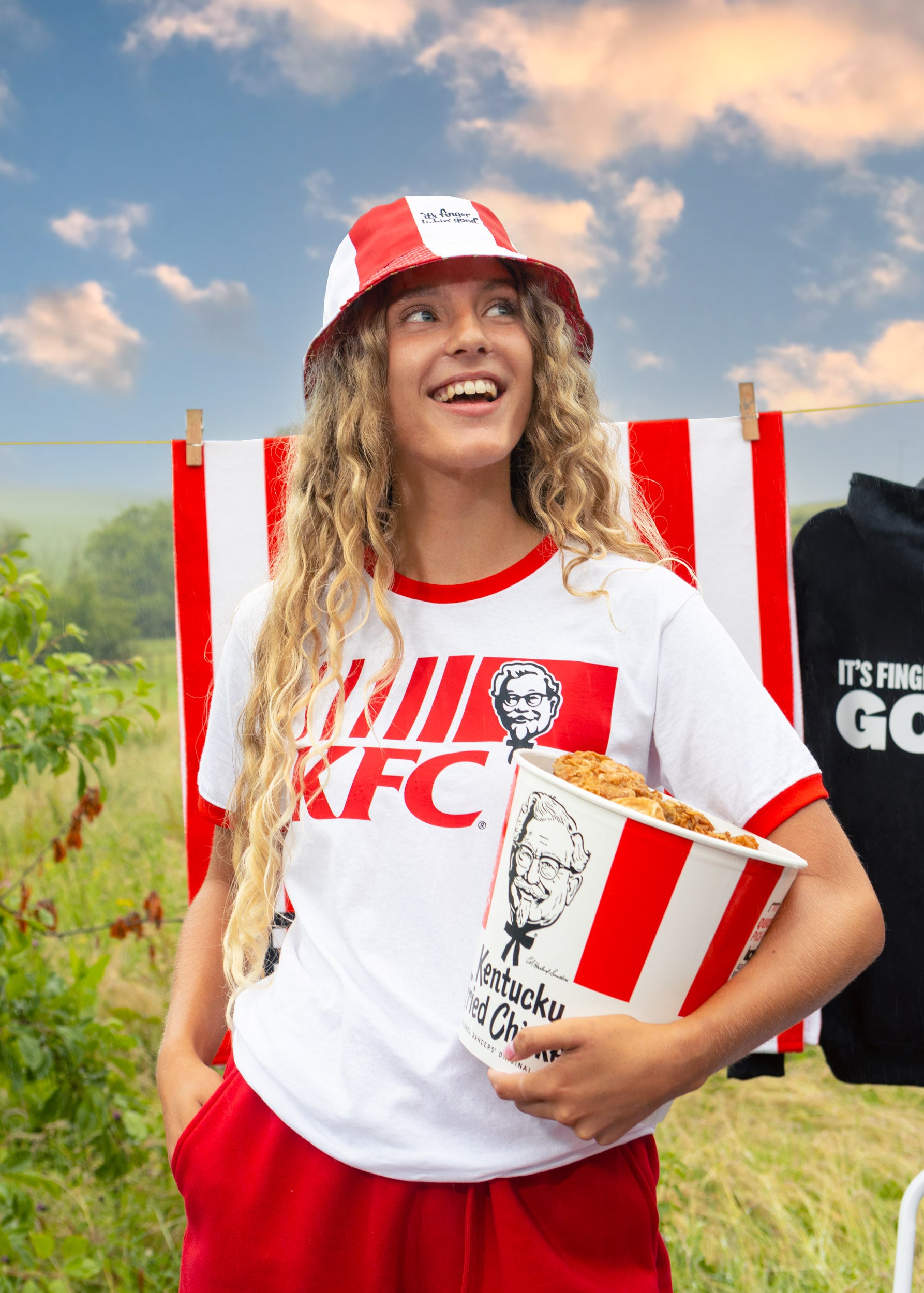 model outside holding KFC bucket wearing head to toe KFC merchandise